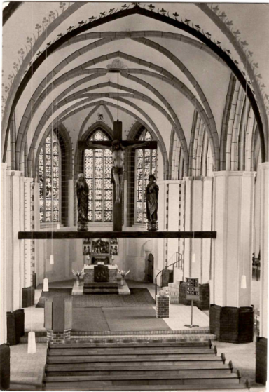 Innenansicht einer Kirche mit hohen Gewölben, Altar und zwei Statuen.